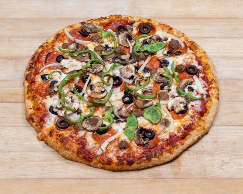 A whole pizza with pepperoni, sausage, mushrooms, green peppers, onions, and black olives.